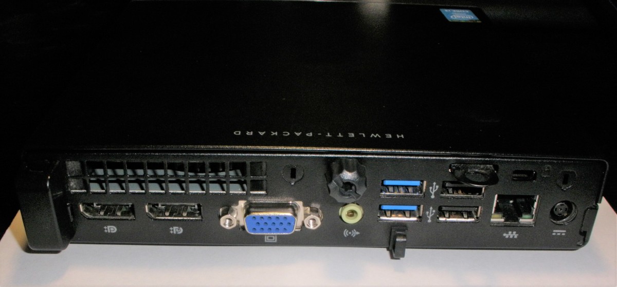 The rear of an HP ProDesk 600 G1 DM.  Unplug the power adapter and all peripherals before opening it to service.     The cover is secured by the single thumb-screw at the rear-center of the PC.