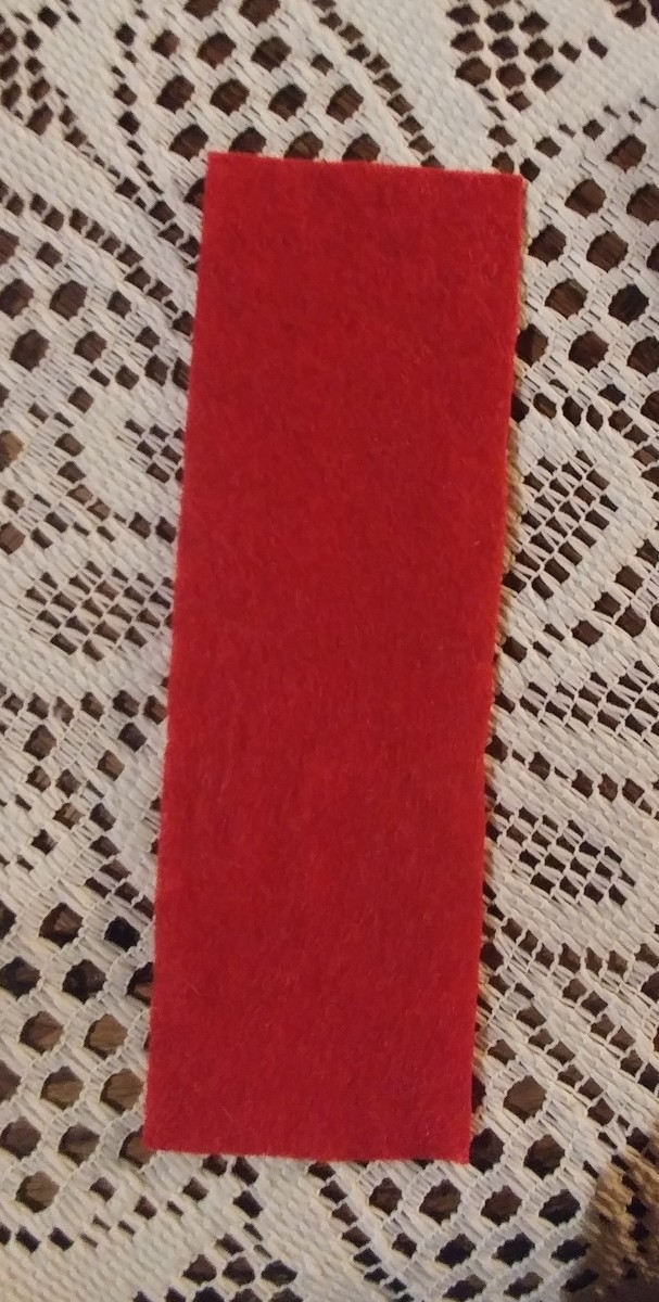 Cut red felt the 7 by 2 and a quarter inches. 