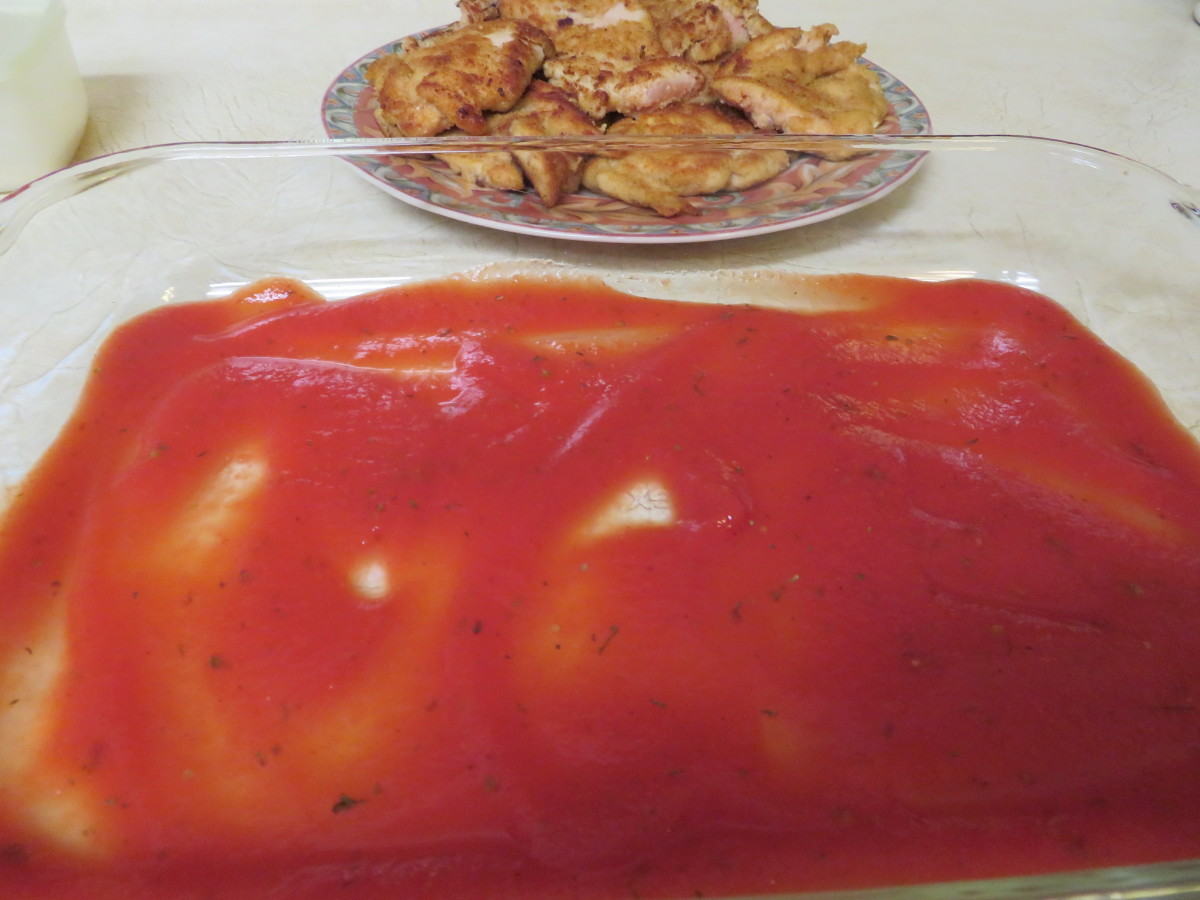 A layer of herbed tomato sauce on the bottom of a baking dish
