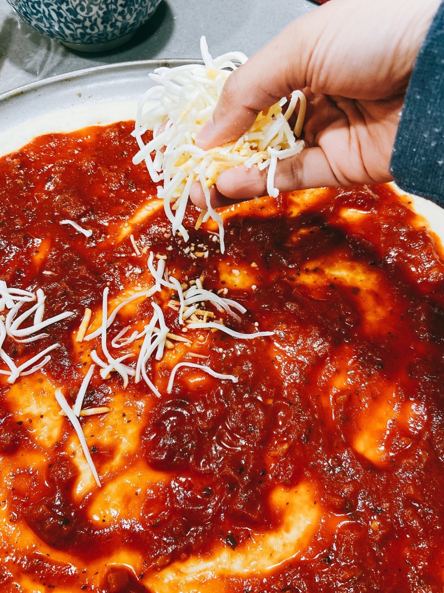 Start topping the dough with the shredded Parmesan and cheddar. 