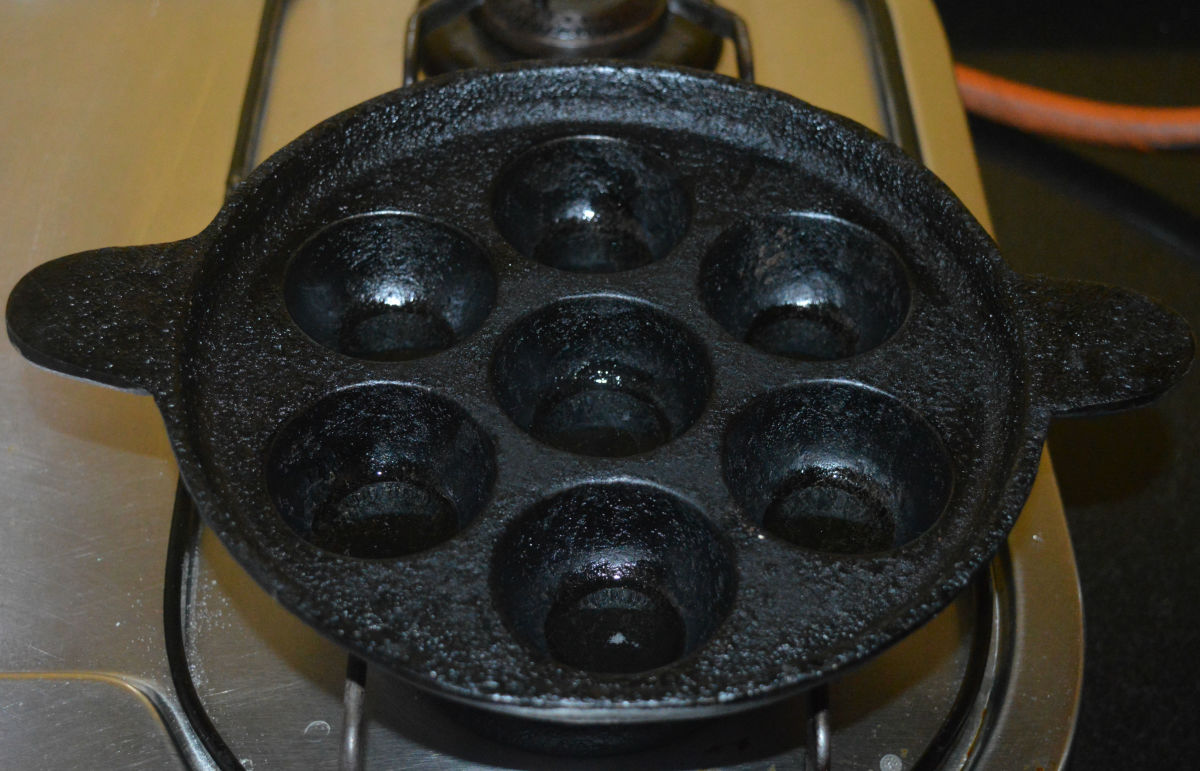 Step five: Heat a pan with cavities. Keep the heat at medium-high. Add a quarter teaspoon oil to each cavity. Place a ball in each cavity. Keep turning each of them occasionally with a spoon to ensure uniform roasting on all sides. 