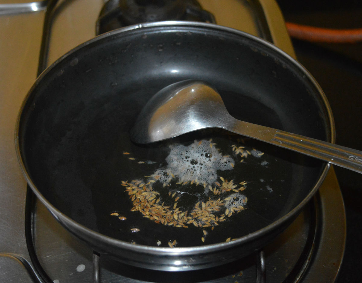 Step one: Making the dough. Heat oil in a deep bottomed pan. Throw in cumin seeds and allow them to crackle.