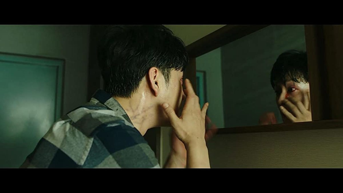 Neighbor (Lee Hyun-wook) looks at the mirror to see himself succumbing to the infection