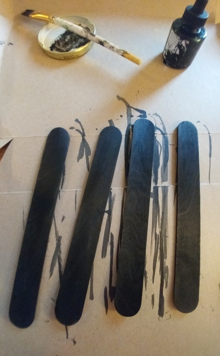 Paint lollipop sticks black. I used large sized lollipop sticks. Some people prefer a small bookmark, so this same process may be repeated with smaller sizes.