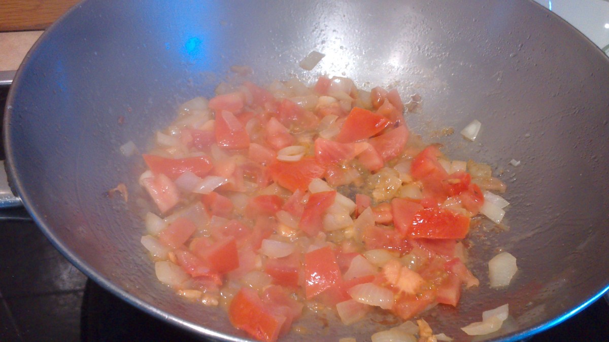 adding the tomatoes to the garlic and onions