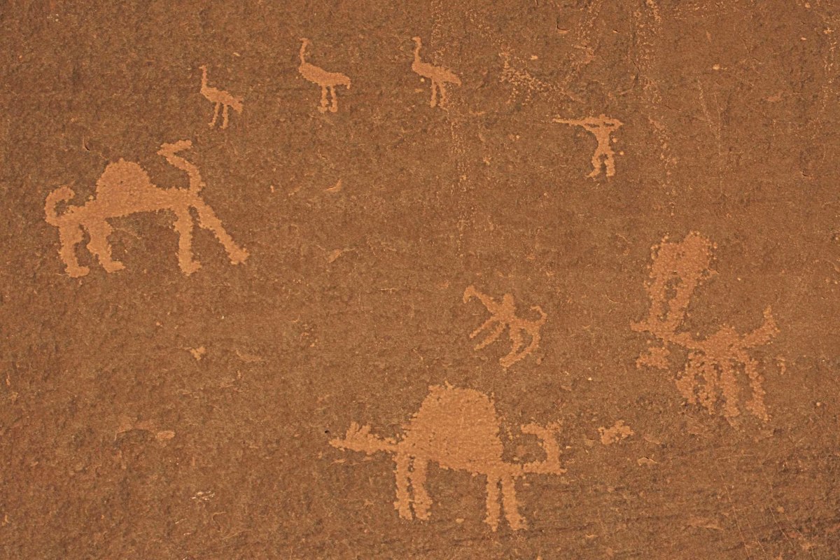 Ancient petroglyphs - rock carvings - in Wadi Rum. The age of these carvings by nomadic travellers seems uncertain, but undoubtably date back thousands of years. In this image are a man with a spear, camels, and the now extinct Arabian ostrich