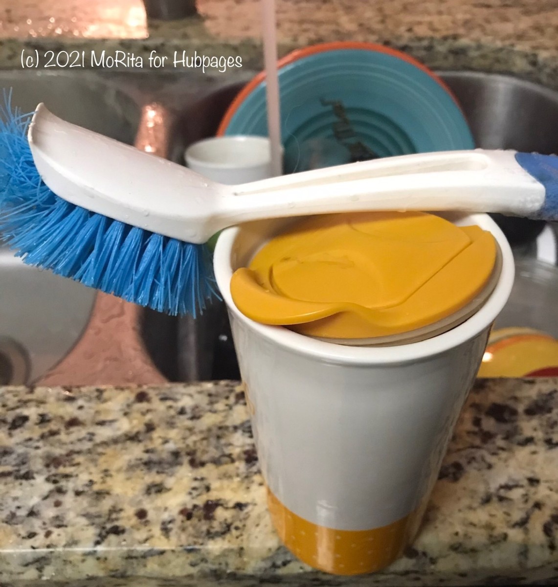 A dish brush and a ceramic cup containing bleach, dish soap, and water provide a quick way to clean dishes throughout the day.