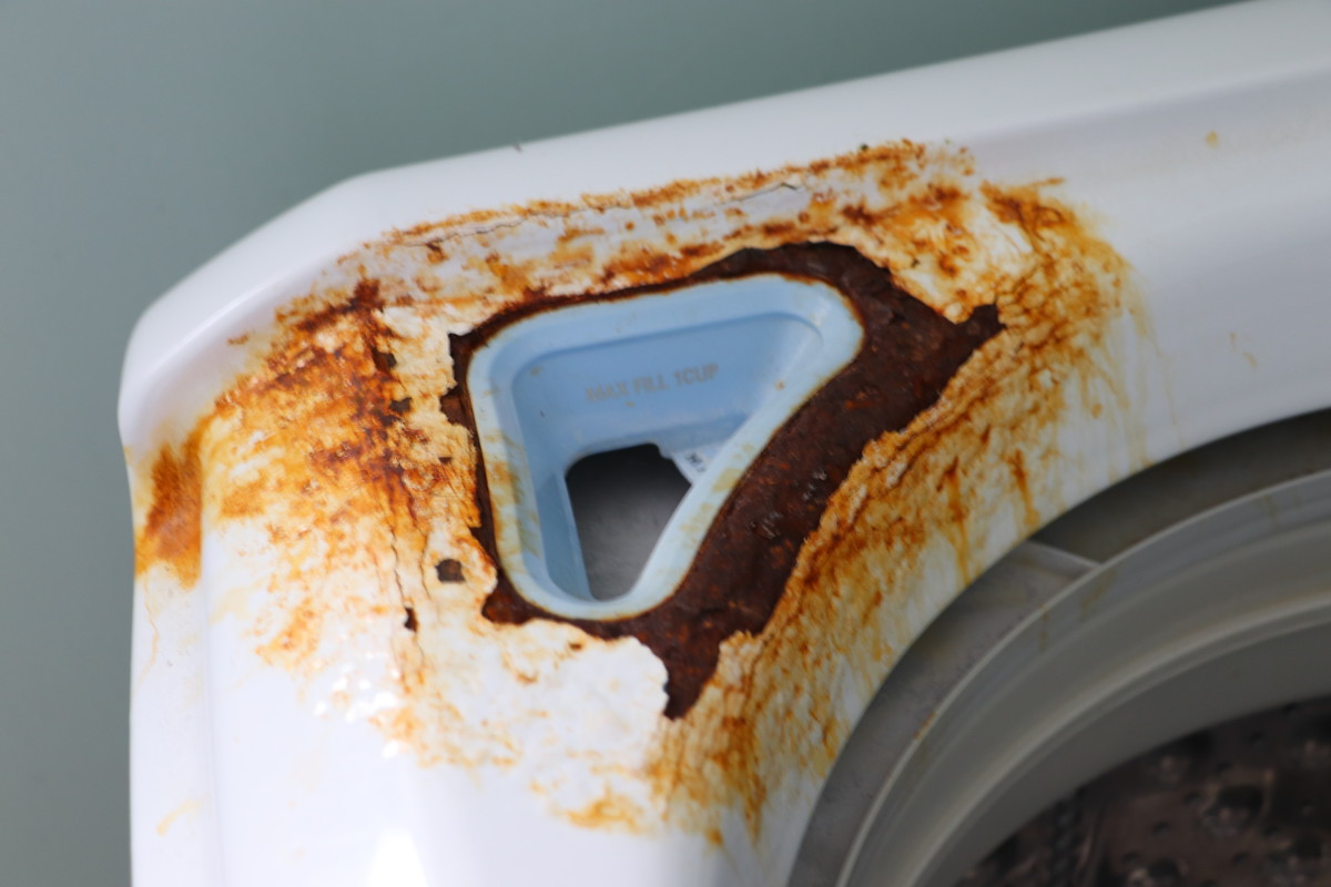Rust has completely corroded through the metal of this washing machine. Earlier attention to the problem would have prevented the oxidation from destroying the metal. This damage cannot be fixed with sanding and repainting. 