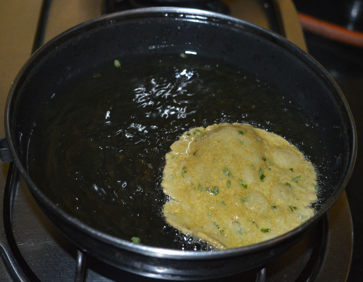 Step three: Heat the oil for deep-frying. Slide a raw poori in the hot oil. Fry it until it puffs up and gets golden brown on both sides. Transfer it to an absorbent paper towel to remove the excess oil.