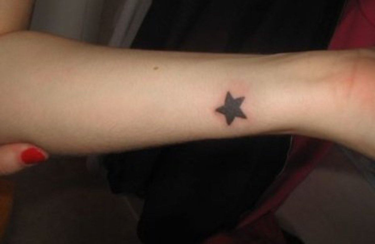 A small, filled-in black star tattoo.