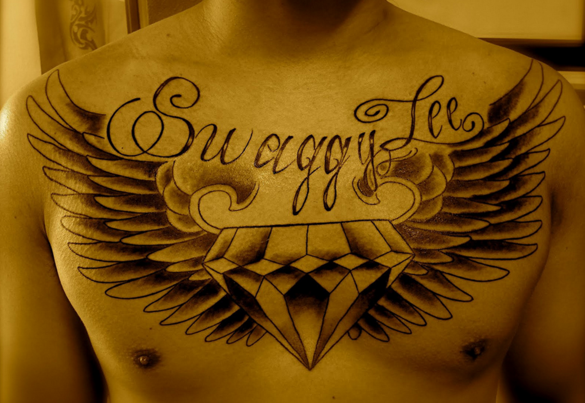 A chest-spanning diamond tattoo with a name inscribed above it.