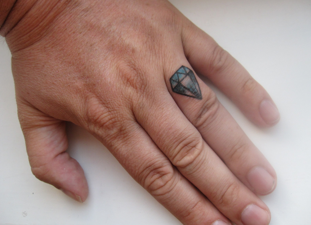 A diamond tattoo on the wearer's ring finger, perhaps symbolizing love, marriage, or committment.