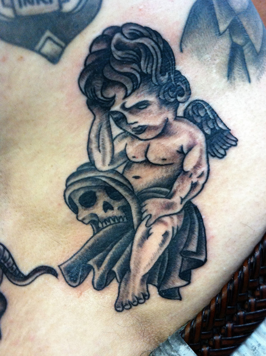 An angel or cherub tattoo that incorporates a skull in its design.
