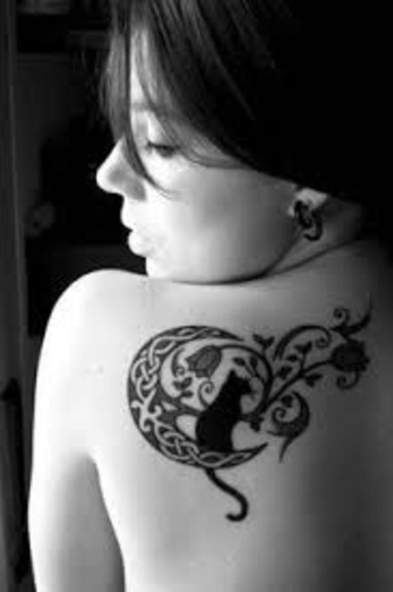 This tattoo, which includes a cat, a crescent moon, and floral elements, exudes feminine energy.