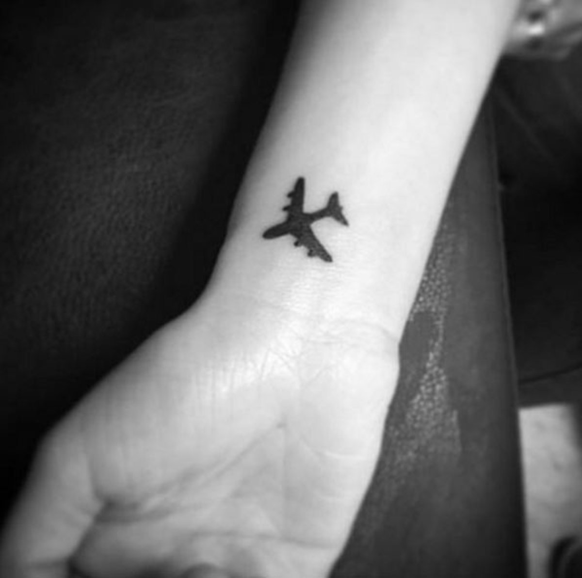 Airplane tattoo located on the wrist, minimalistic