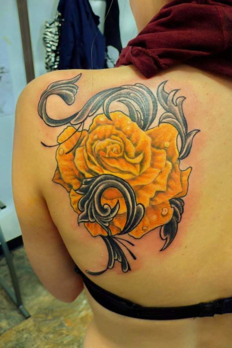 A yellow rose with twining leaves on the shoulder.