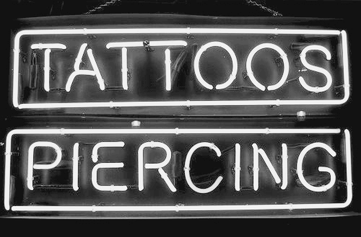 Neon signs advertising tattoos and piercings.