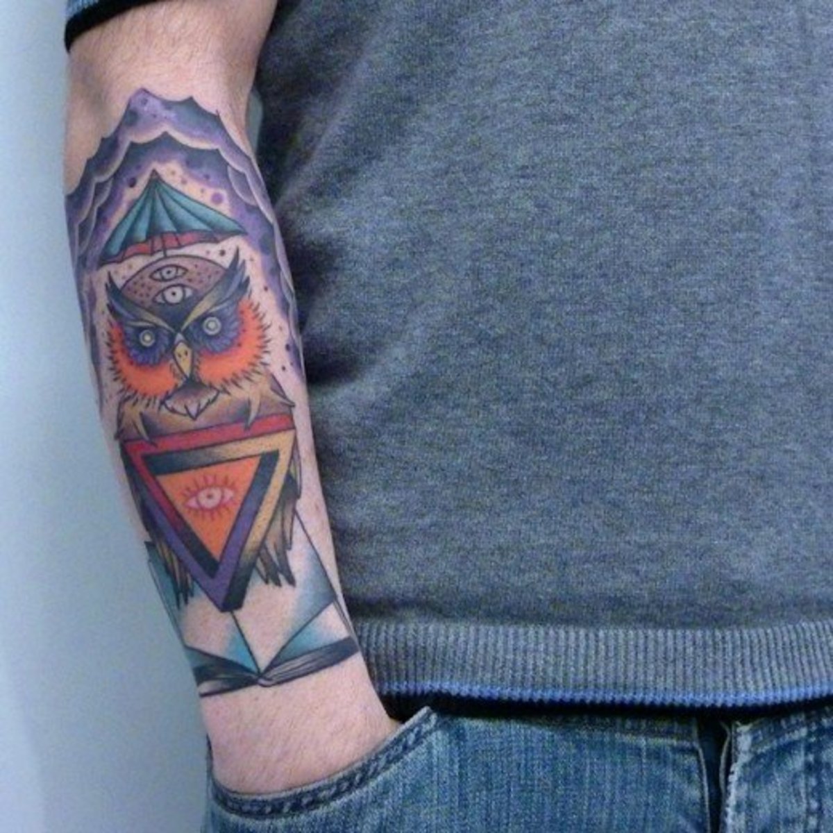 An owl tattoo that incorporates storm clouds, an umbrella, and a book.
