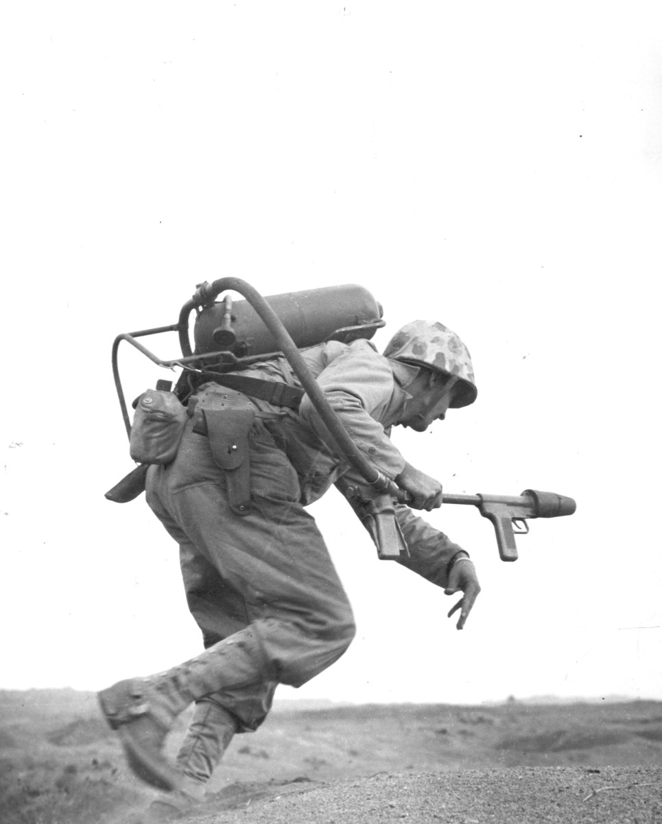 A flamethrower operator of E Company, 2nd Battalion 9th Marines, 3rd Marine Division, runs under fire on Iwo Jima.