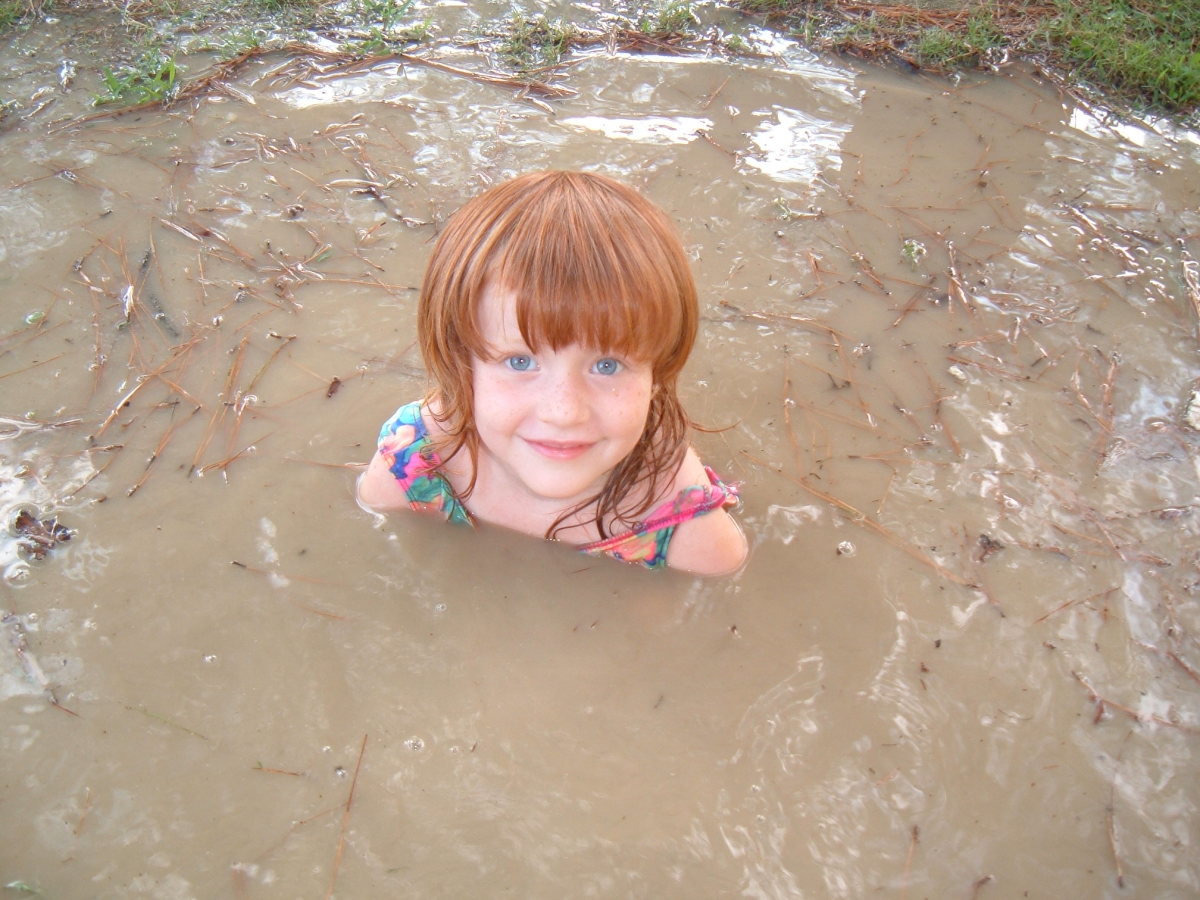 Cuty redhead little girl in mud puddle