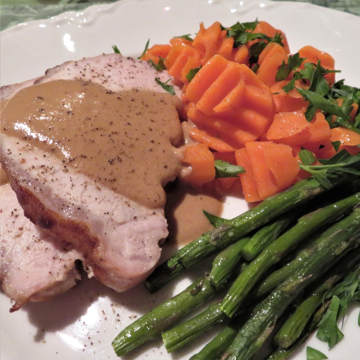 Roasted pork napped with mustard sauce, baked asparagus, and crinkle-cut carrots with chopped parsley