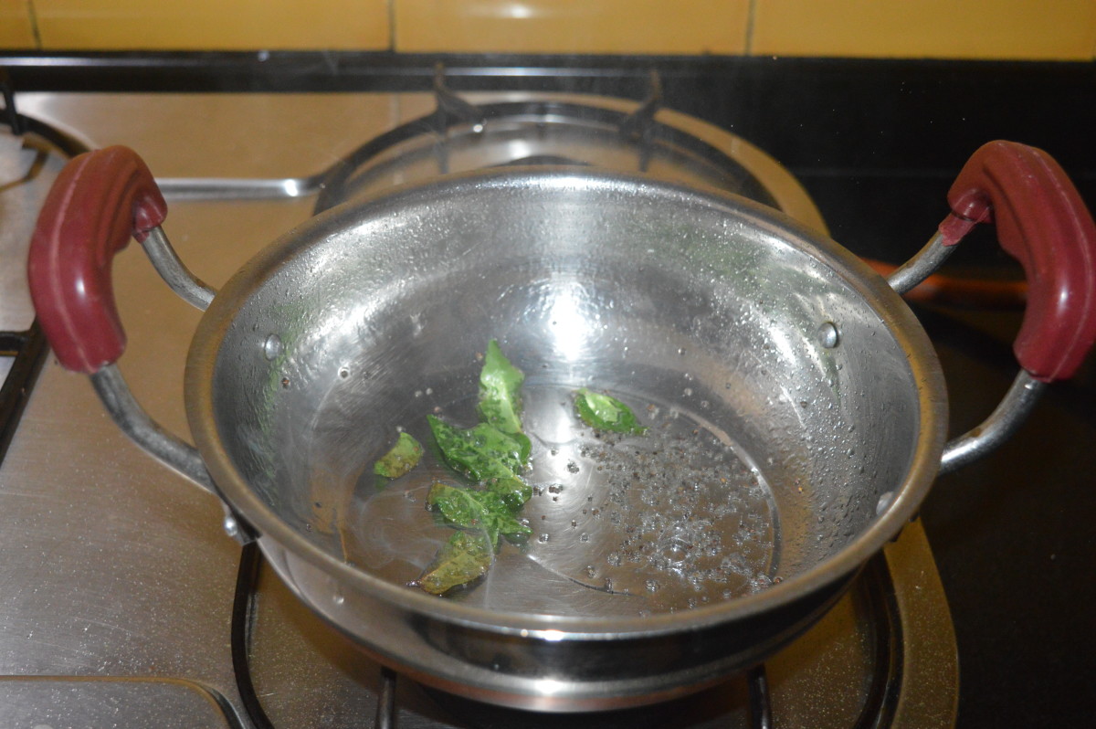 Step four: Heat oil in a deep bottomed pan. Throw in mustard seeds. Allow it to crackle. Add curry leaves and mix well.