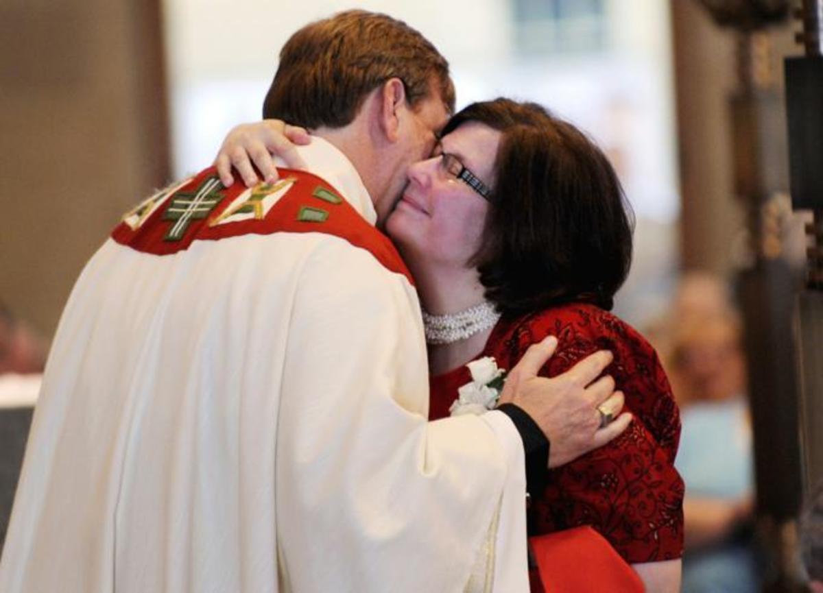 Father Scott Caton being hugged by his wife during his ordinary as a catholic priest in Rochester- N.Y