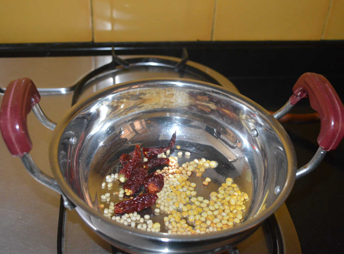Step one: Heat some oil in a deep bottomed pan. Add split chickpeas, white lentils, and broken dry red chilies.