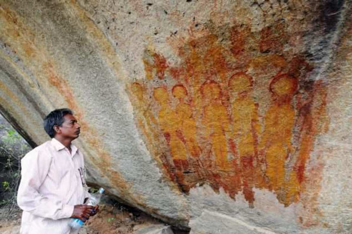 An unknown man views these 10,000-year old rock paintings in Chhattisgarh, India. The painting appears to depict UFOs and alien beings. Artist is unknown.