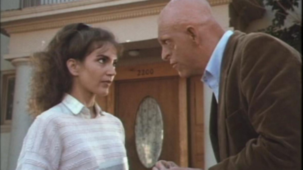 Diane (Brinke Stevens) goes over final details to a house she's renting from Herman (Michael Berryman)