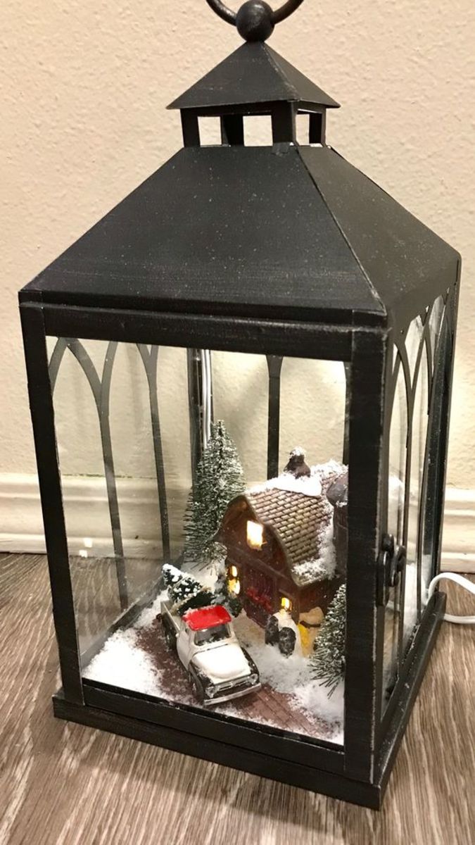 This lantern features a snowy scene of a truck bringing home the freshly cut Christmas tree.