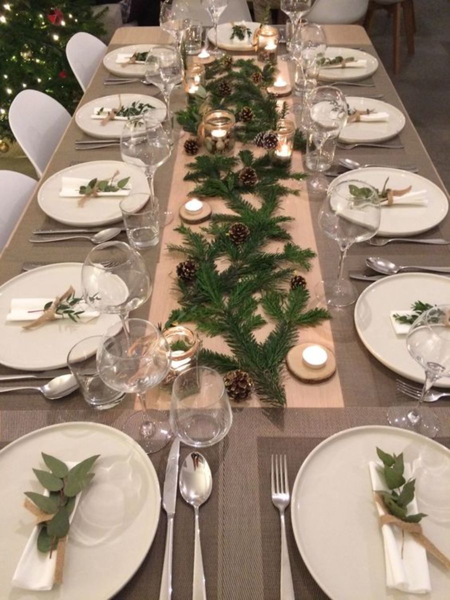 I love how simple this table runner is: beige cloth paired with evergreen boughs and pinecones. The napkin holders are tied with sprigs of herbs!