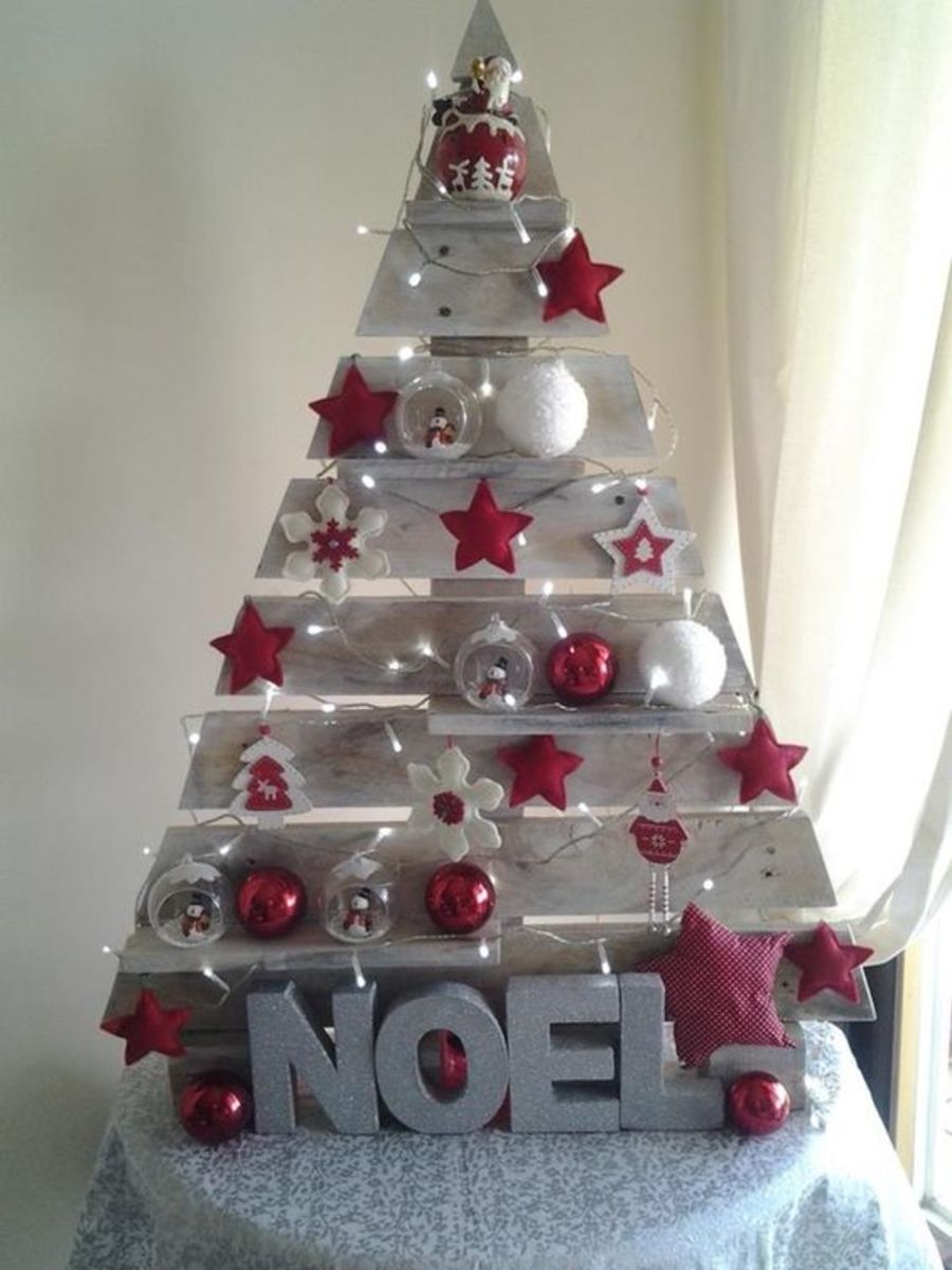 This pallet Christmas tree is decorated with white paint and baubles in red and white.