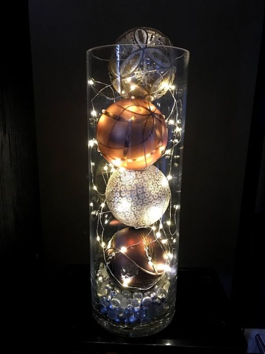 This idea is so simple: Fill the bottom of the vase with glass table scatter, stack four ornaments inside it, and place string lights down the sides.