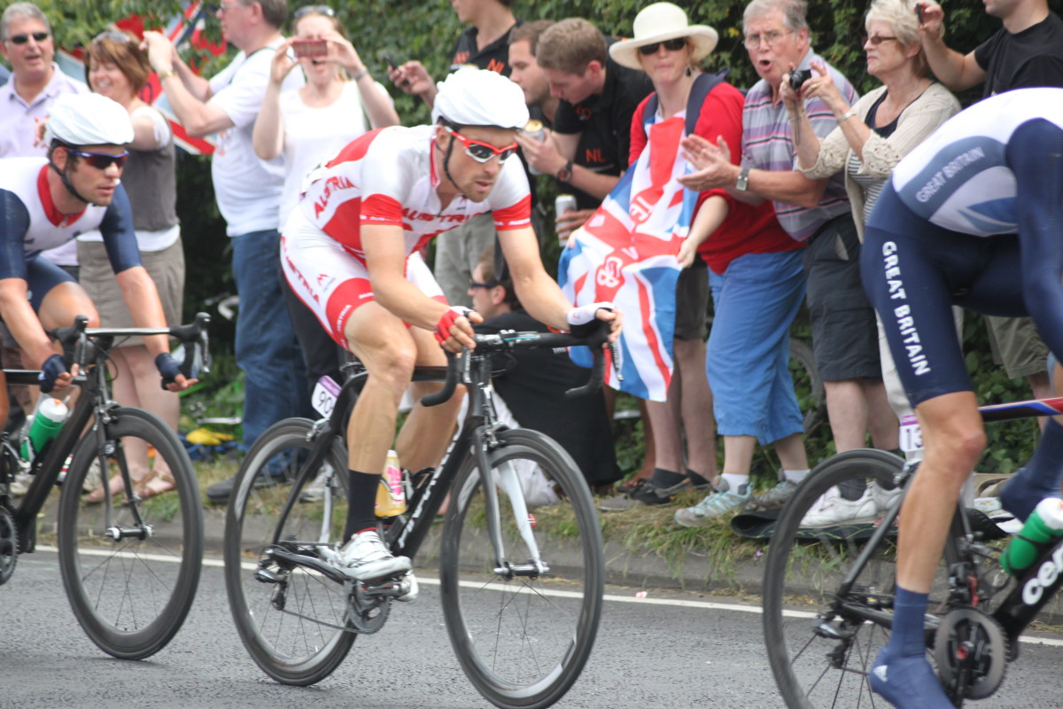 Mark Cavendish and Bernard Eisel in the London 2012 Olympic Cycling Road Race wearing a helmet with a cover for additional aerodynamic advantage