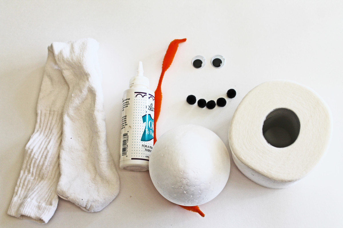 Here are the basic things you need to make this snowman: a tube sock, tacky glue (or hot glue gun with sticks), chenille stem,  googly eyes, small pom poms, styrofoam ball and a roll of toilet paper.