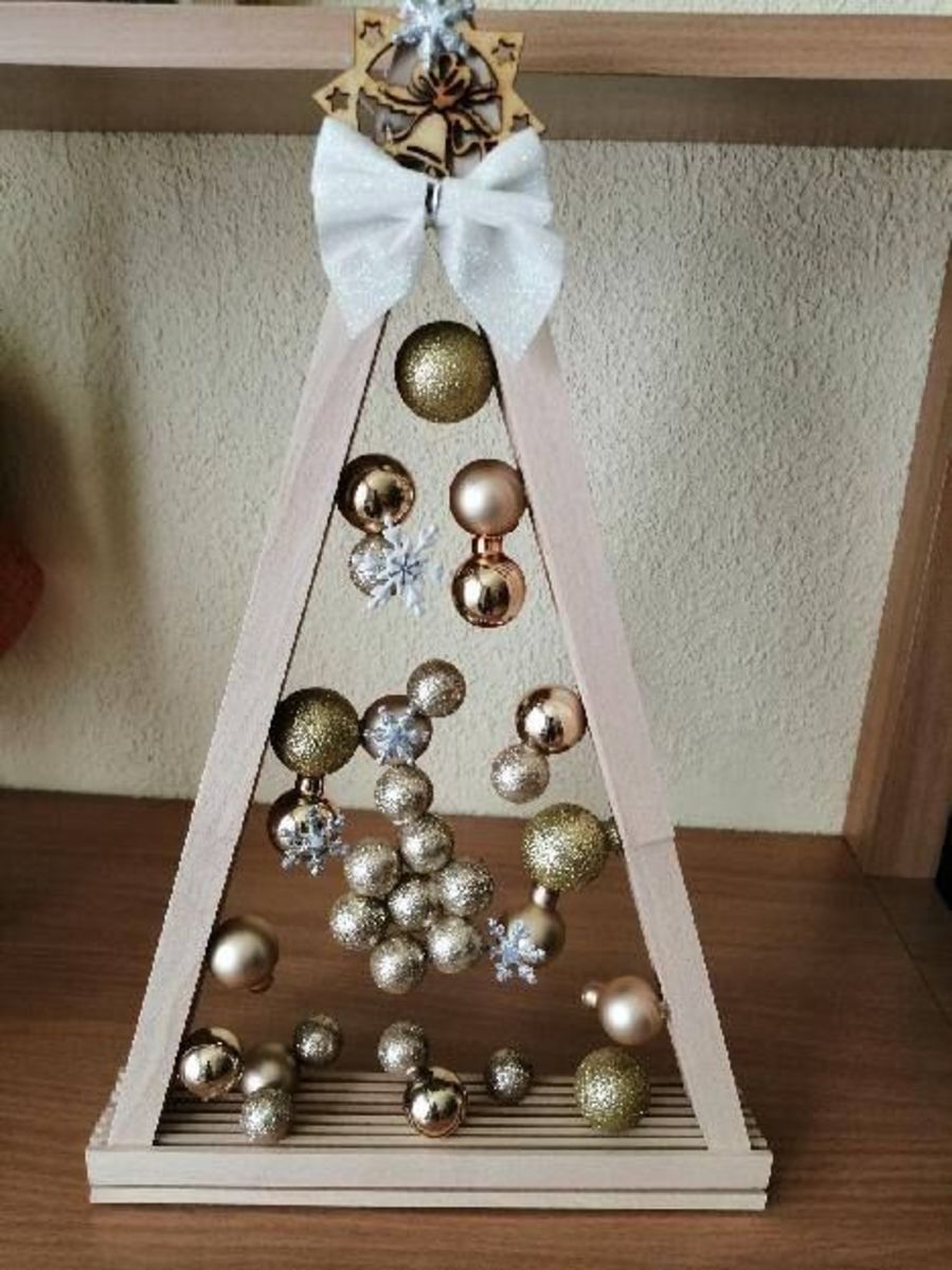 This natural wooden tree is decorated with gold baubles and a white ribbon.