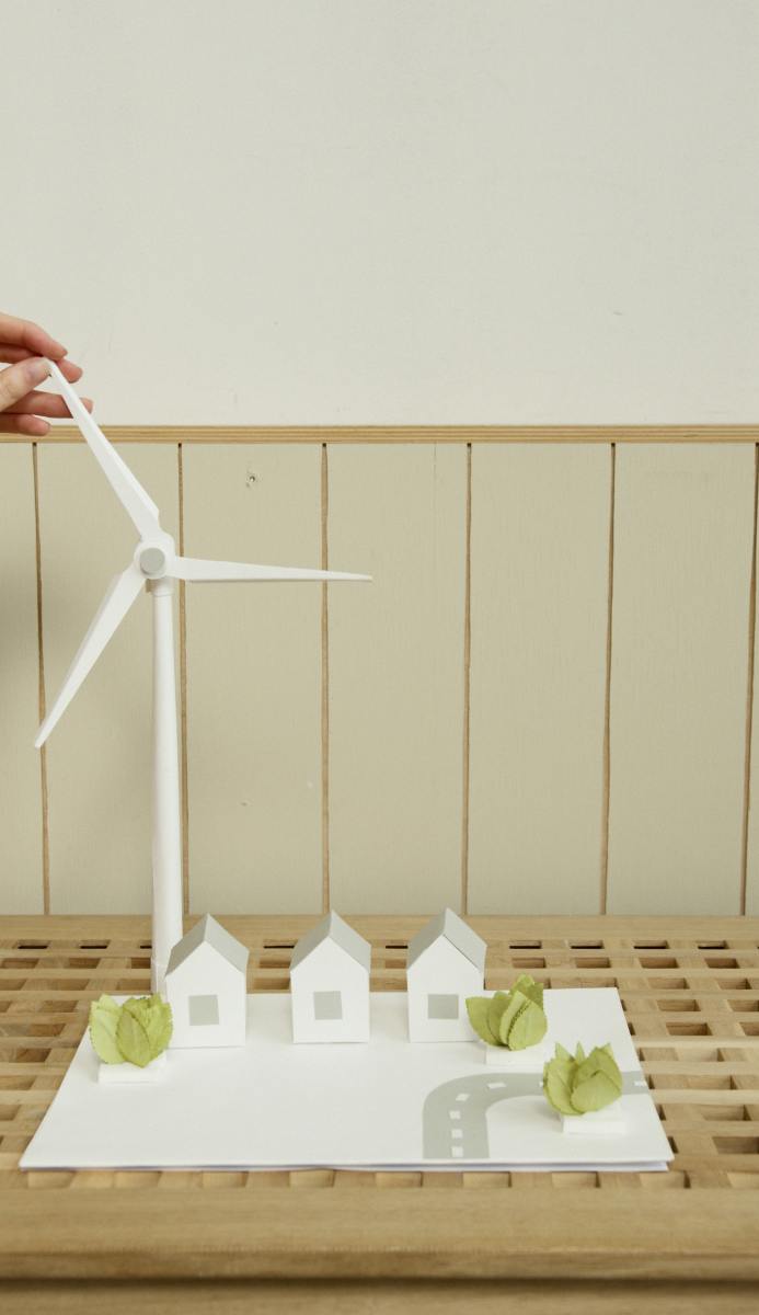 A scale model of houses with a wind turbine made with cardboard.