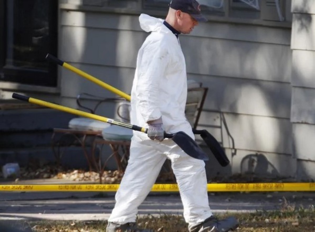 An investigator brings two shovels into the yard of the Irwin’s to search for evidence. Photo courtesy of AP/Orlin Wagner.