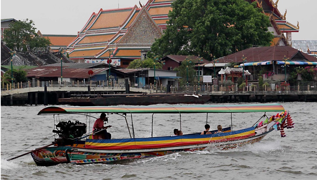 One of the long-tail boats speeds past a temple complex - boating on the rivers and canals is a good way to see many of the key sights of Bangkok