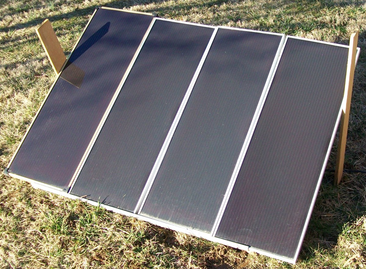 Four panels arranged on a makeshift ground frame in the yard.  The panel on the far left did not come with the original kit yet it works just fine with the other three and they all produce 60 watts in full sun.