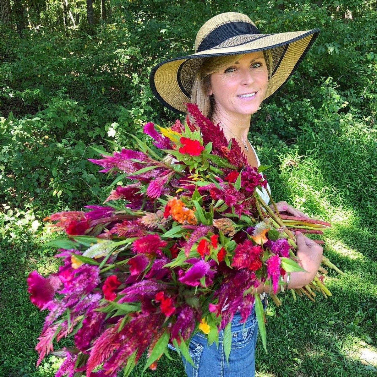 Kelly Lehman holding an enormous bouquet of celosia at her flower farm. 