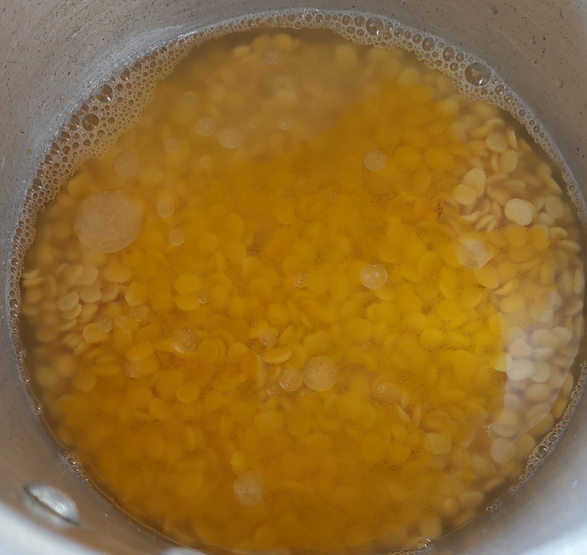 Transfer soaked lentils to a cooker. Add 1 cup of water and 1/2 teaspoon of turmeric powder