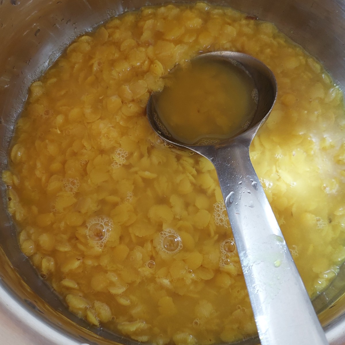 When the pressure of the cooker releases naturally, open the lid and transfer the lentils to a vessel. Mash the lentils until they are smooth with the back of a ladle or whisk.