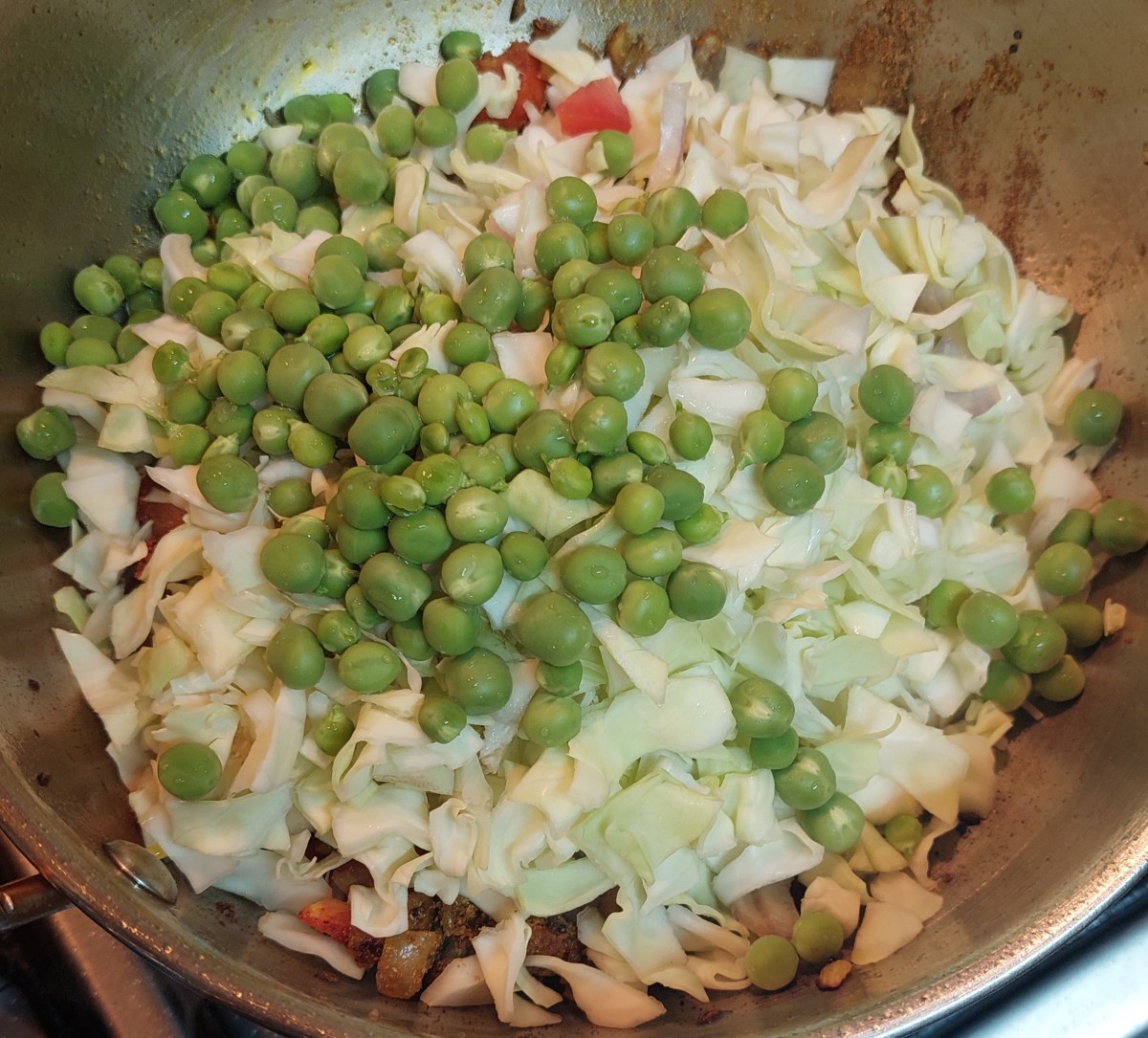 Add chopped cabbage and peas, mixing well with the spices. 