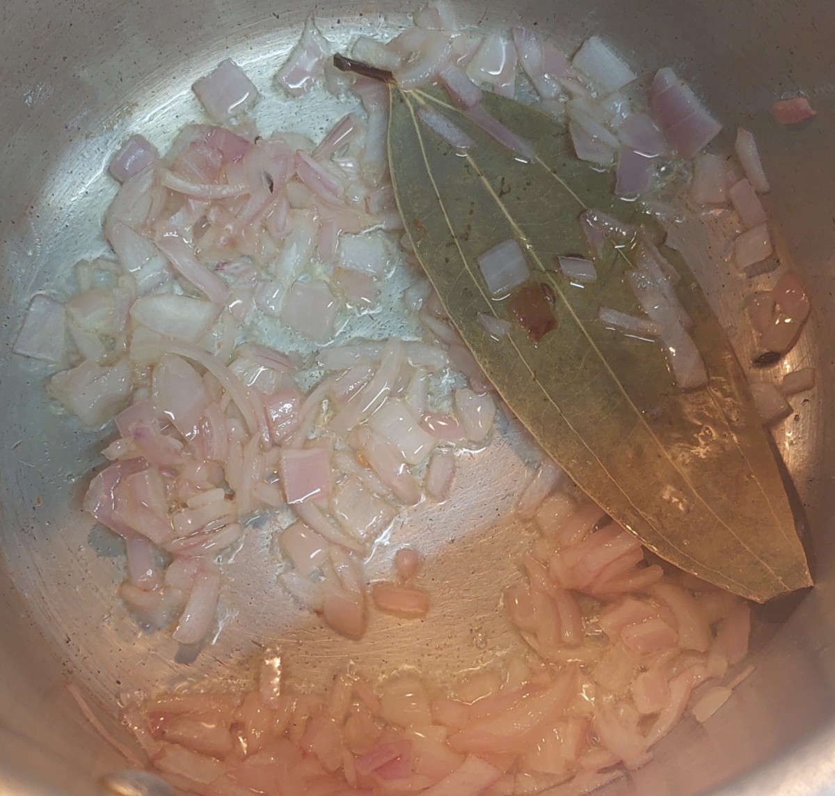 In a cooker, heat 1 tablespoon of oil. Add bay leaf and finely chopped onion. Fry till onion turns translucent.