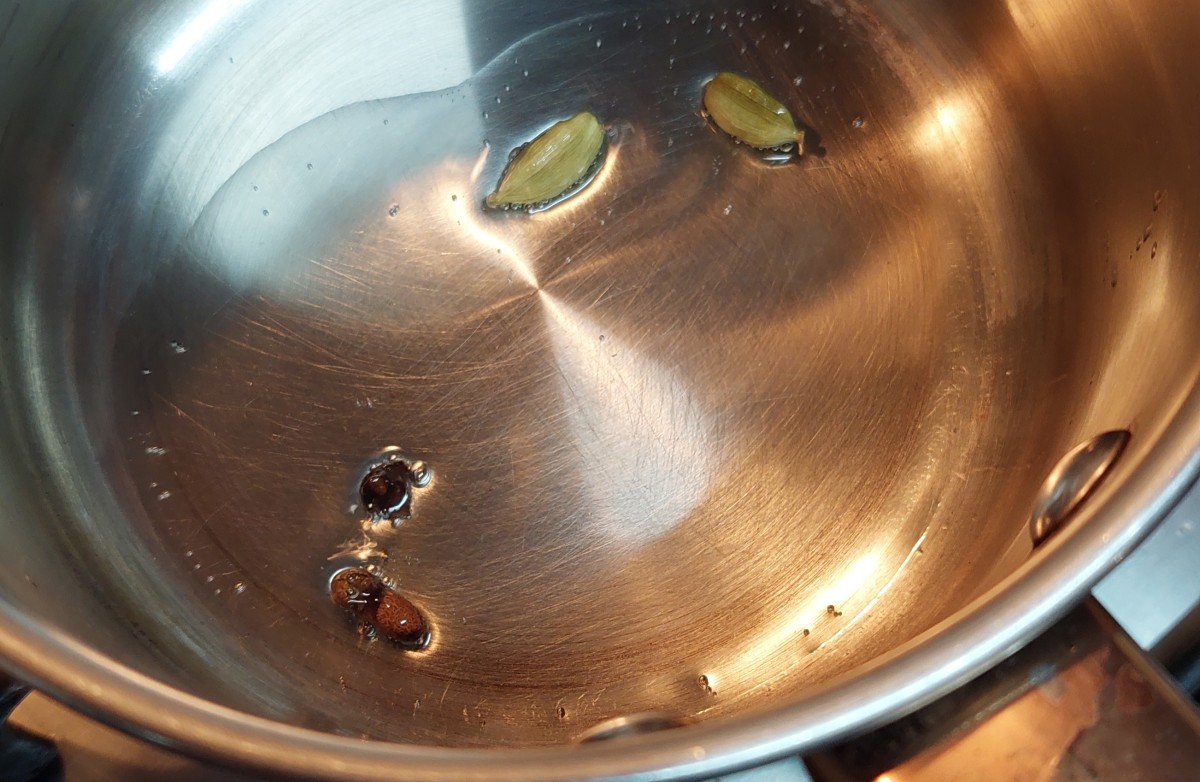 In a pan, heat 1 tablespoon of oil. Add 1-2 cloves and 1-2 cardamom pods. Fry for a few seconds.