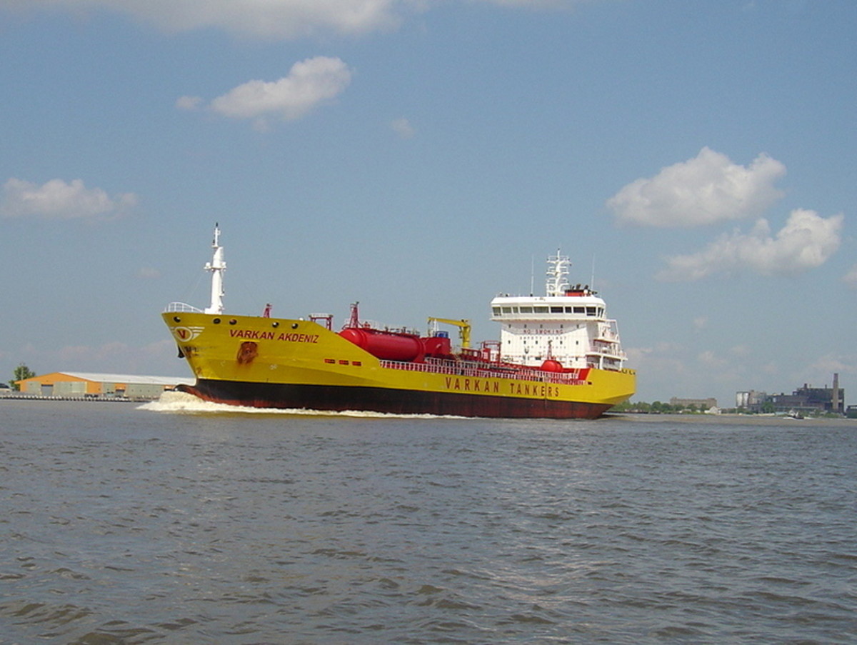A large yellow tanker owned by a Middle Eastern company carries petroleum products on the Mississippi River heading toward New Orleans.