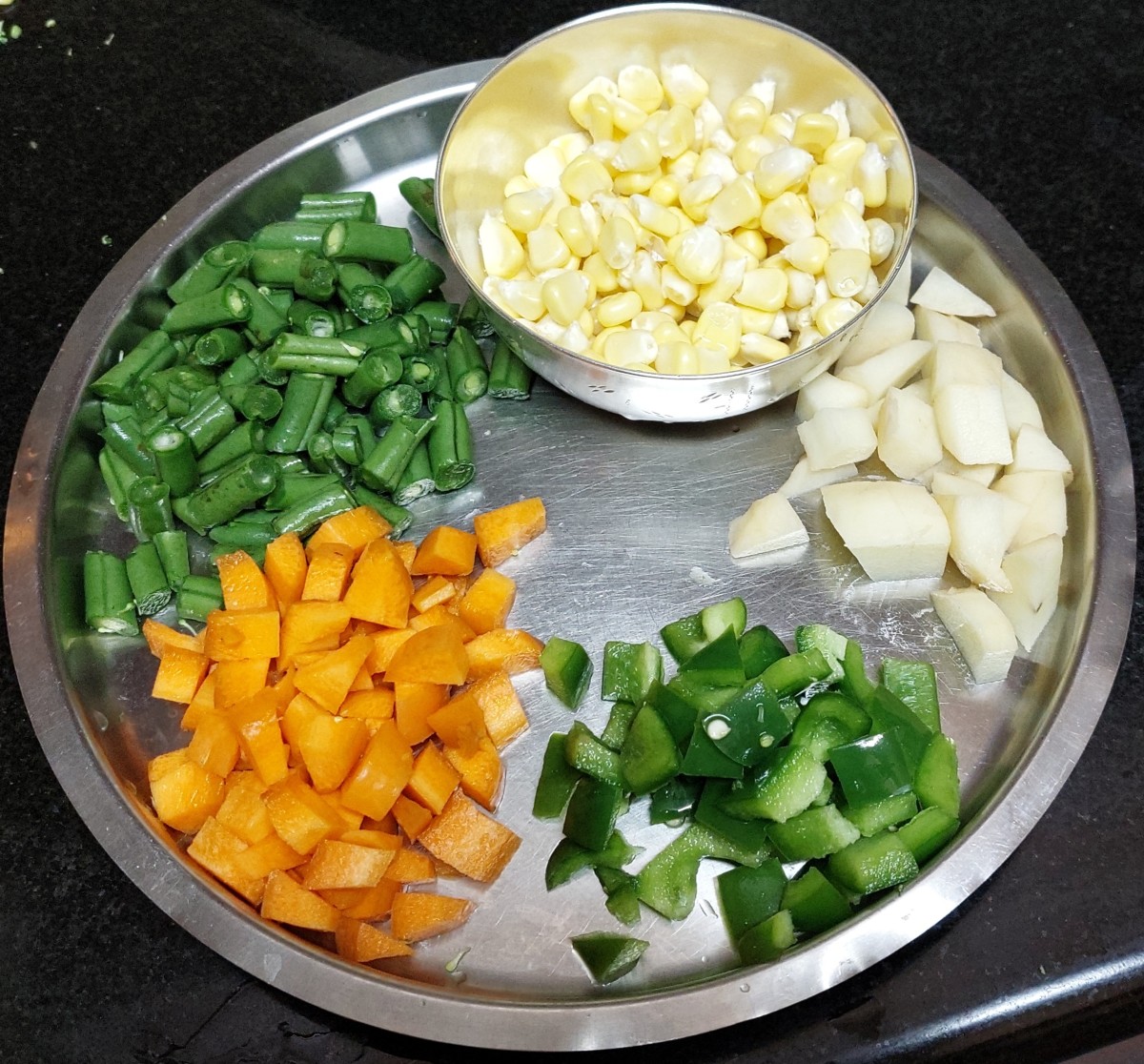 Wash and chop French beans, carrots, and capsicum. Peel and chop potatoes. Keep sweet corn ready. Set aside.