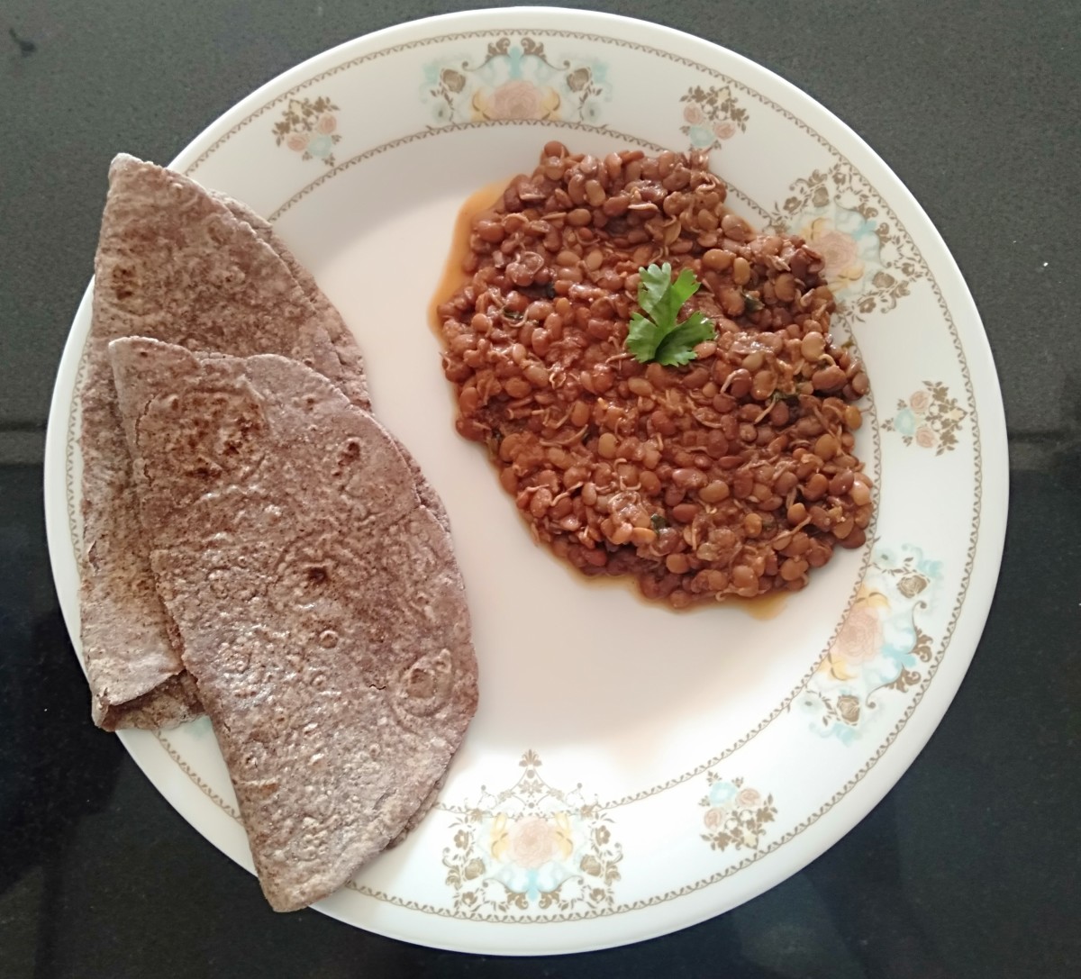 Sprouted horse gram curry garnished with coriander leaf and millet roti